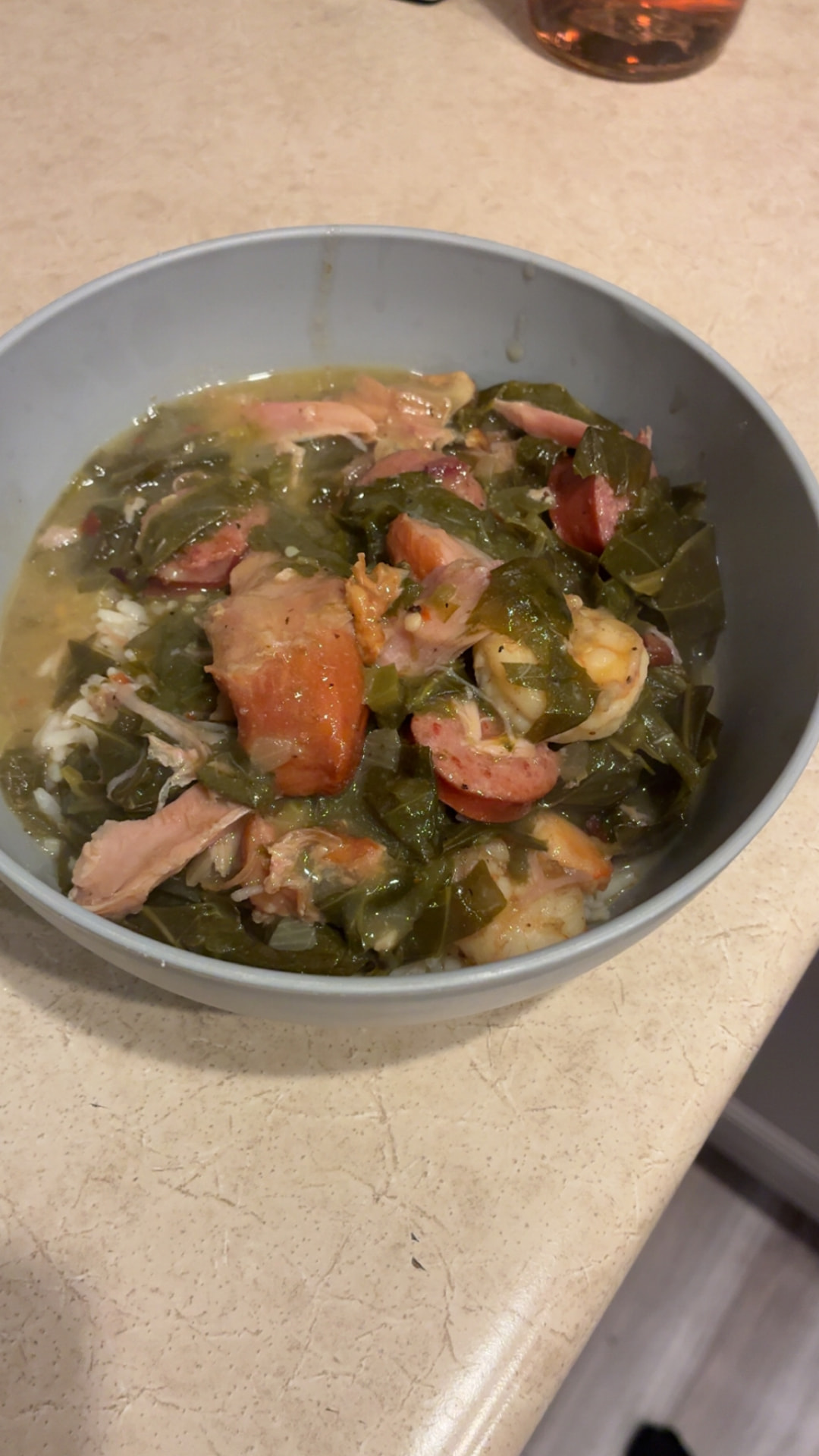 Bowl of collard greens over rice with smoked turkey and sausage